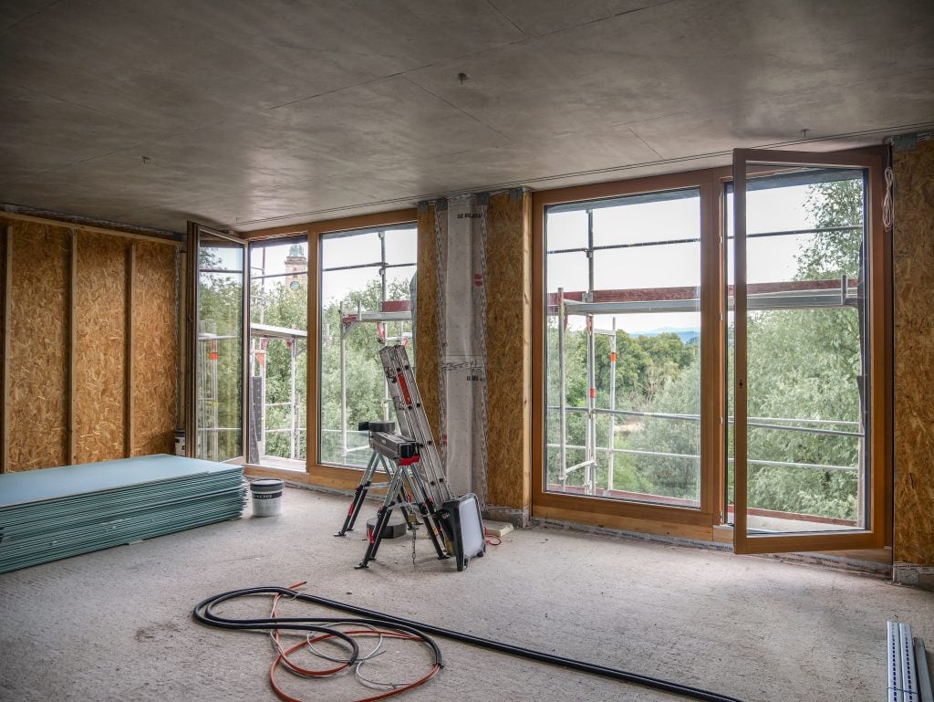 Innenansicht des Belsers Hotel im Rohbau mit großen Holzfenstern, Blick auf den Neckar und die Altstadt von Nürtingen mit Kirchturm.