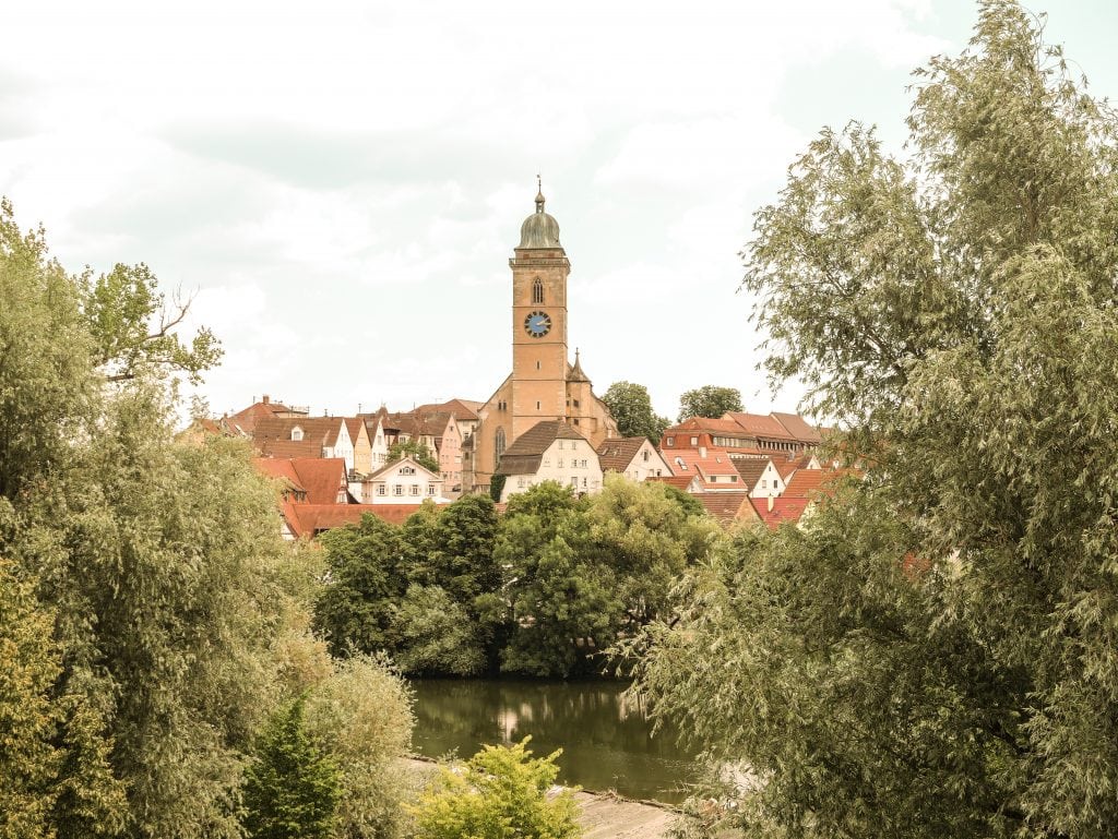 Blick auf die Altstadt von Nürtingen mit der Stadtkirche St. Laurentius, roten Dächern und dem Neckar im Vordergrund.