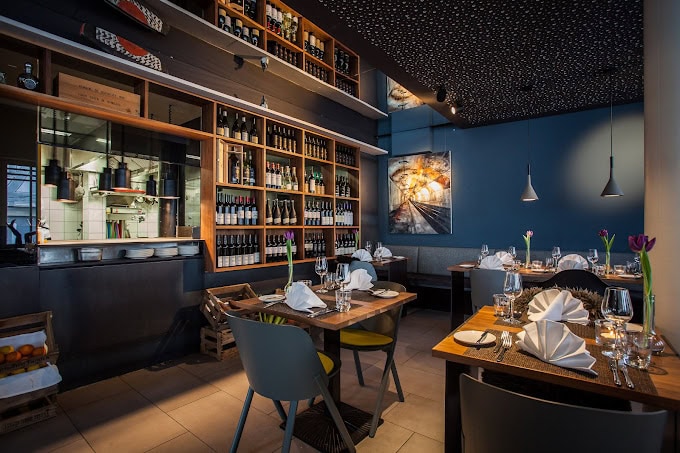 belsers Restaurant in Nürtingen: moderner, eleganter Gastraum mit bodentiefen Fenstern, sichtbarer Küche und hochwertiger Ausstattung – stilvoll, hell und einladend.