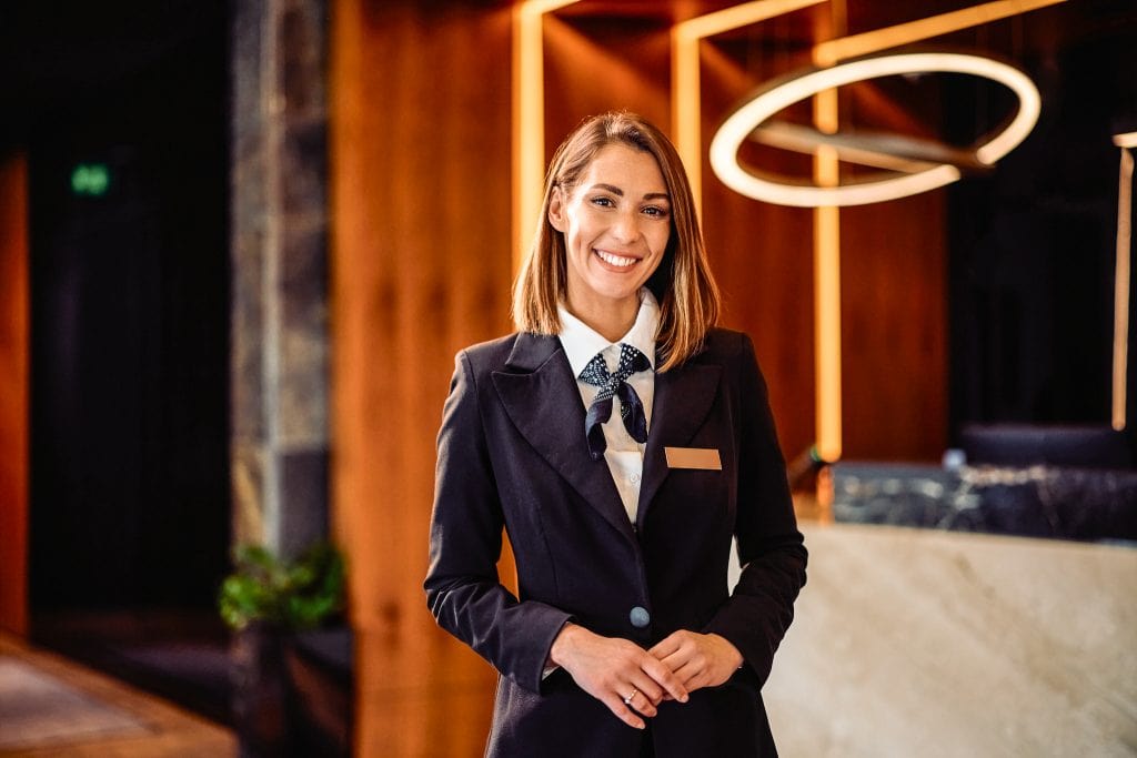 Hotelempfang, freundliche Rezeptionistin im Belsers Hotel, lächelnd am Empfang.