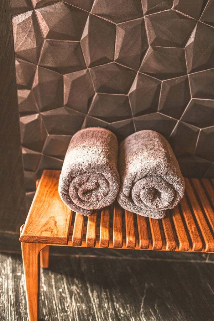 Weiche Handtücher auf Holzbank im Spa-Bereich von Belsers Hotel, luxuriöser Wellness-Urlaub.