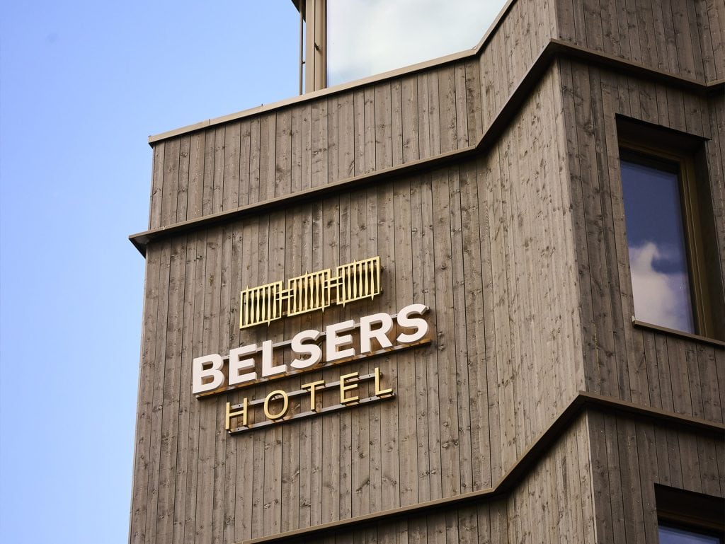 Modernes Hotelgebäude aus Holz mit Belsers Hotel Logo, ideal für einen komfortablen Aufenthalt in einer stilvollen Umgebung. Perfekt für Gäste, die Natur und Design verbinden möchten.