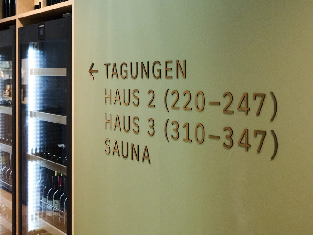 Innenansicht des Belsers Hotels mit Hinweisschildern zu Tagungsräumen und Sauna, modernes Design, freundliche Atmosphäre, ideal für Geschäftsreisende und Erholungssuchende.