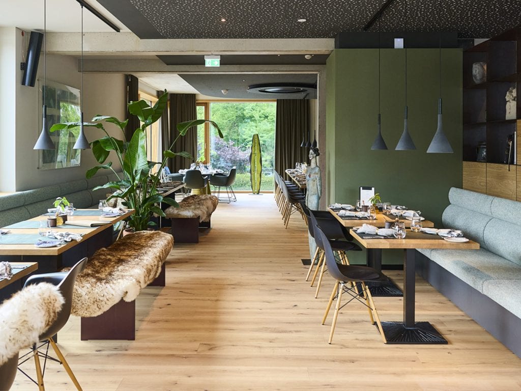 Helles Hotelrestaurant im Belsers Hotel mit stilvoller Einrichtung, großen Fenstern und komfortablen Sitzgelegenheiten, ideal für Frühstück, Mittagessen oder Dinner.