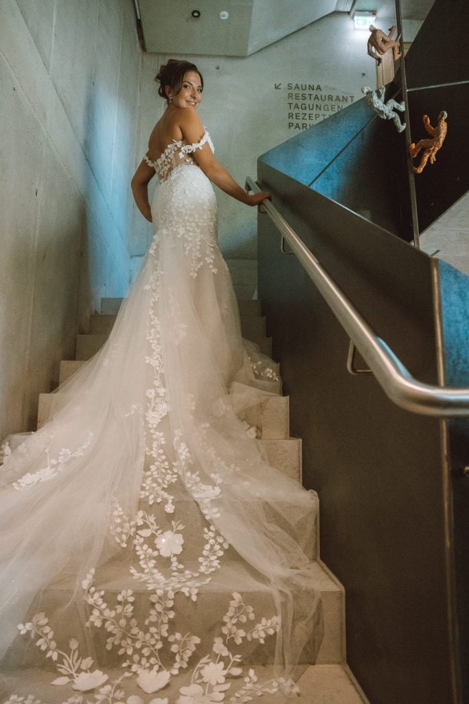 Braut in eleganter Hochzeitskleidung auf Treppe im Belsers Hotel in Nürtingen, modernes Design mit stilvoller Atmosphäre.