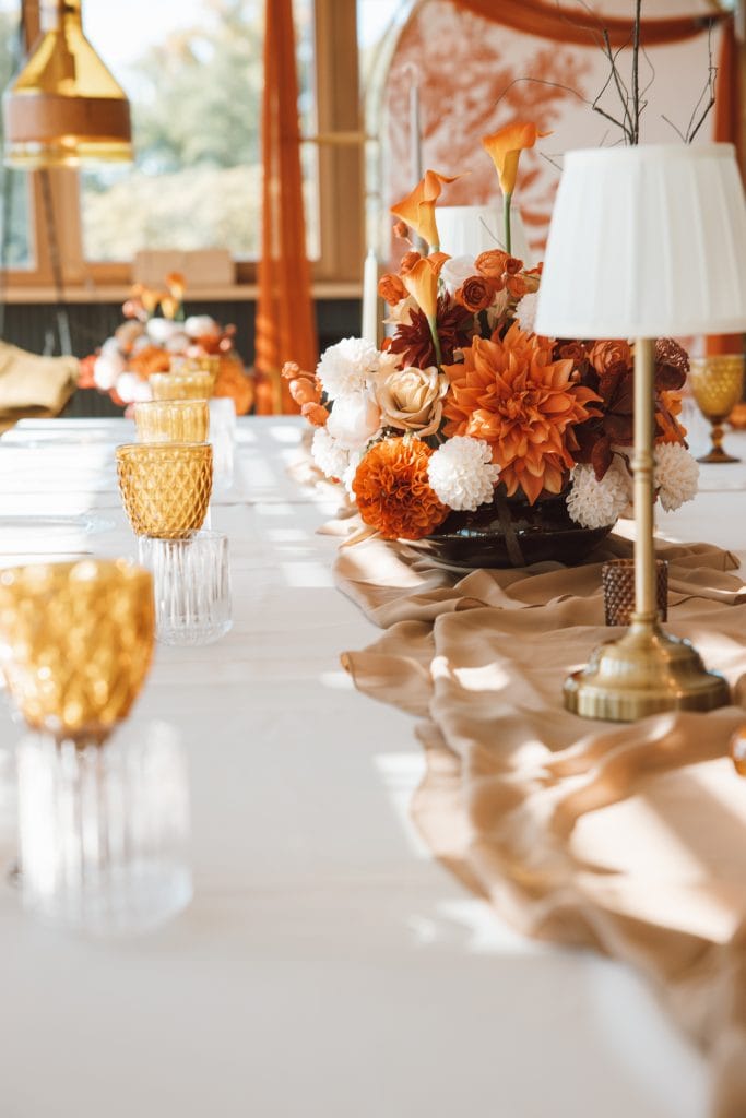 Eleganter Hochzeitstisch mit Blumen, Kerzen und stilvoller Dekoration in warmen Orangetönen bei Belsers Hotel Nürtingen.