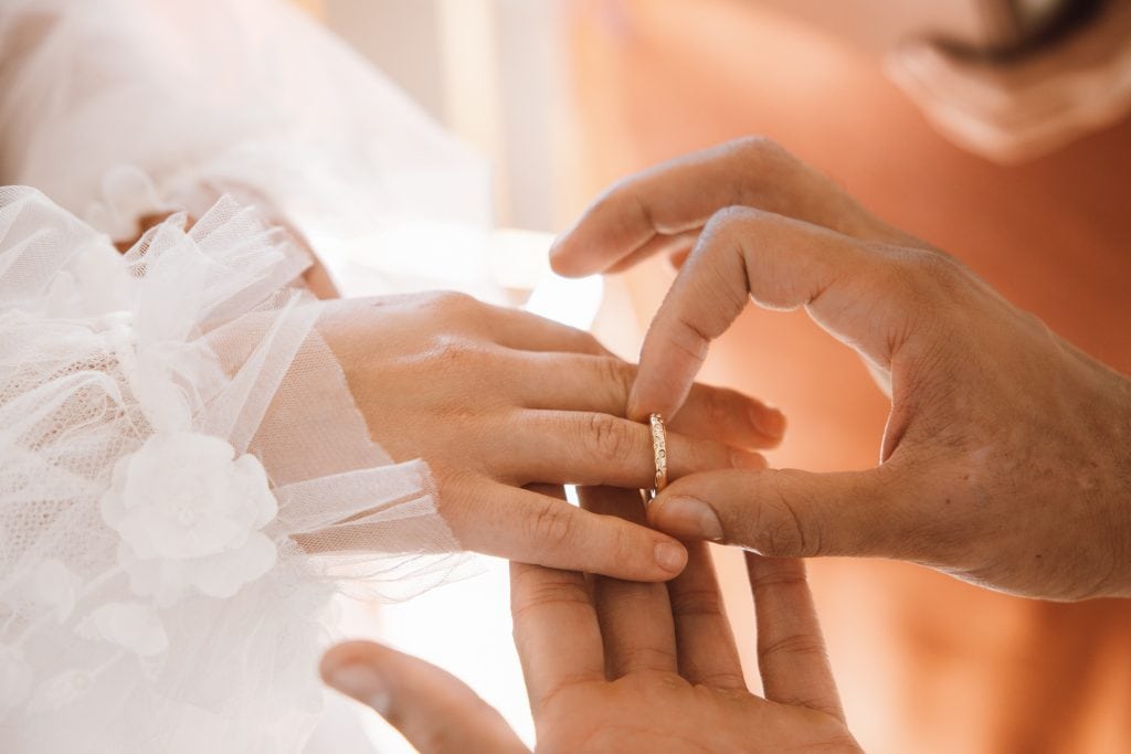 Hände bei einer Hochzeit, das Brautpaar tauscht Ringe in einer emotionalen Zeremonie.